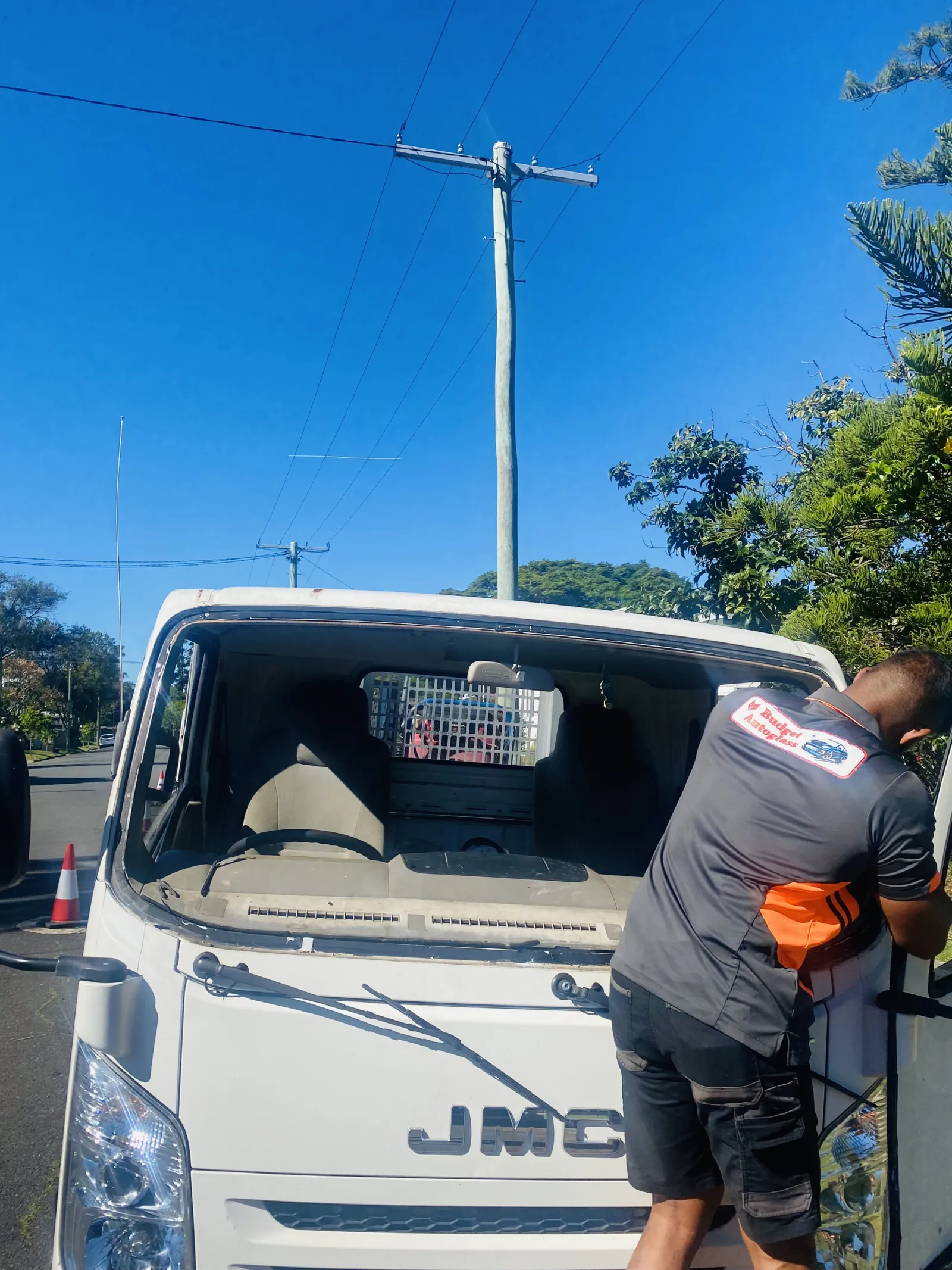 A Budget Auto Glass technician fitting a windscreen to a light truck at the kerb